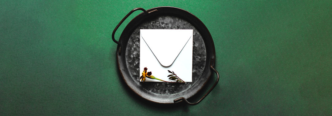 a letter inside of an iron bowl with dried ash and flower beside it