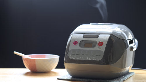 cooking wild rice inside of a rice cooker on table with a pink and white plate